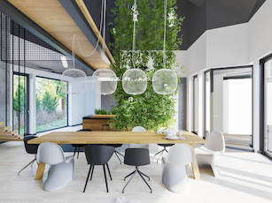 Pokój dzienny w dużym domu z dużym stołem do jedzenia dużą ilością przeszkleń i roślinami na ścianie w barwach naturalnego drewna i szarości