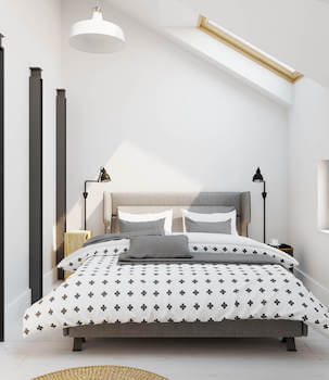 Jasna minimalistyczna sypialnia z szarym łóżkiem w stylu skandynawskim na poddaszu