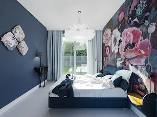 Granatowa sypialnia z dużym łóżkiem z miękkim wezgłowiem tapeta w duże kwiaty i designerska biała lampa na suficie