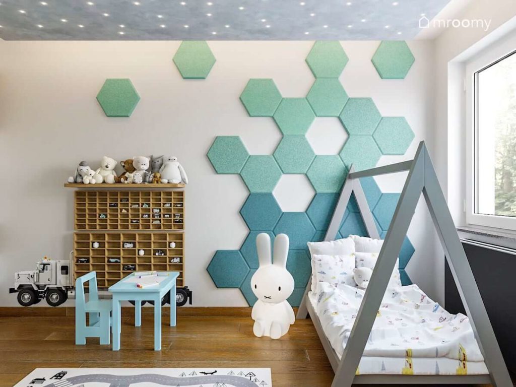Ściana z panelami ściennymi w kształcie heksagonów i łóżko domek z lampką królikiem w pokoju małego chłopca