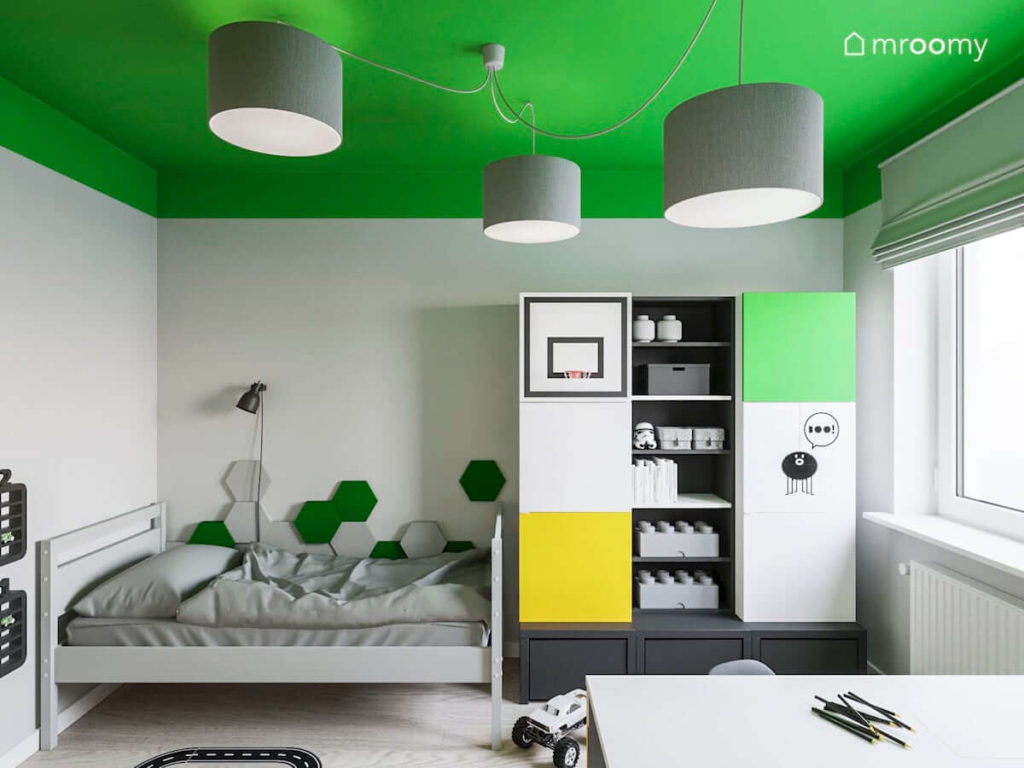 Kolorowe meble vox z szarym łóżkiem w pokoju kilkuletniego chłopca w którym jest zielony sufit i szare lampy z abażurów