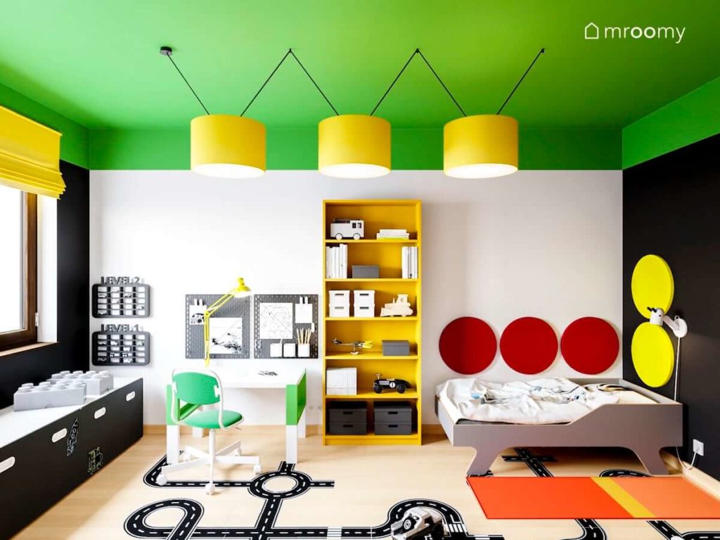 kolorowy pokój małego chłopca z intensywnie zielonym sufitem żółtymi lampami żółtym regałem i czerwonymi okrągłymi panelami na ścianie przy łóżku