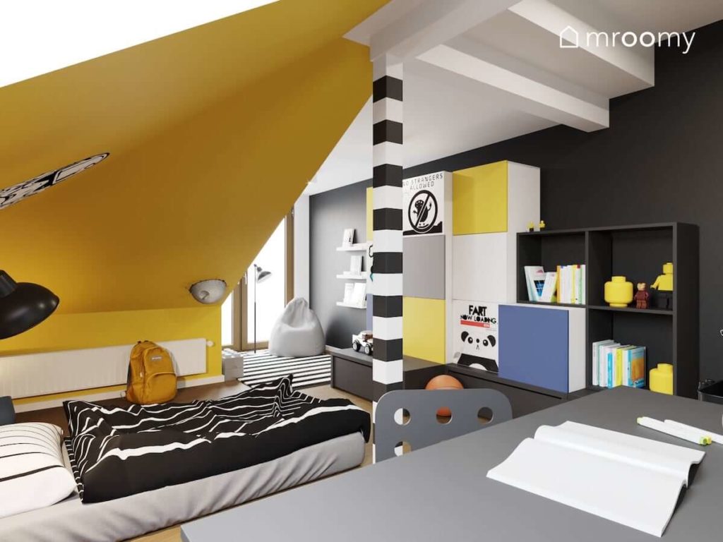 Łóżko w formie materaca leżące na podłodze kolorowe meble na poddaszu z dużymi skosami pomalowanymi na żółto w pokoju nastolatka