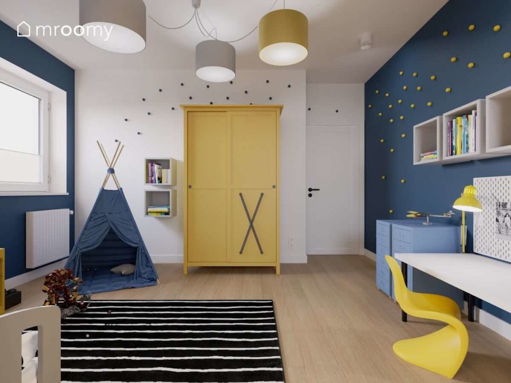 Niebieskie tipi żółta szafa z dodanymi gumowymi strapami i biała ściana z gałkami kropkami w pokoju małego chłopca fana superbohaterów