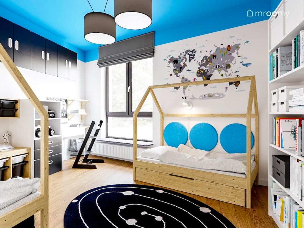 Pokój braci z dwoma łóżkami domkami i biurkiem z krzesłem na podłodze leży czarny dywan z motywem kosmosu a na ścianie naklejka z mapą świata