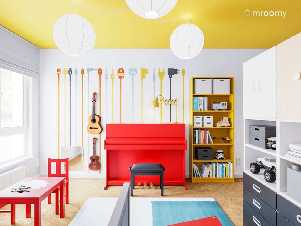 Czerwone pianino kolorowa tapeta i żółty regał w pokoju bawialni dwóch małych chłopców