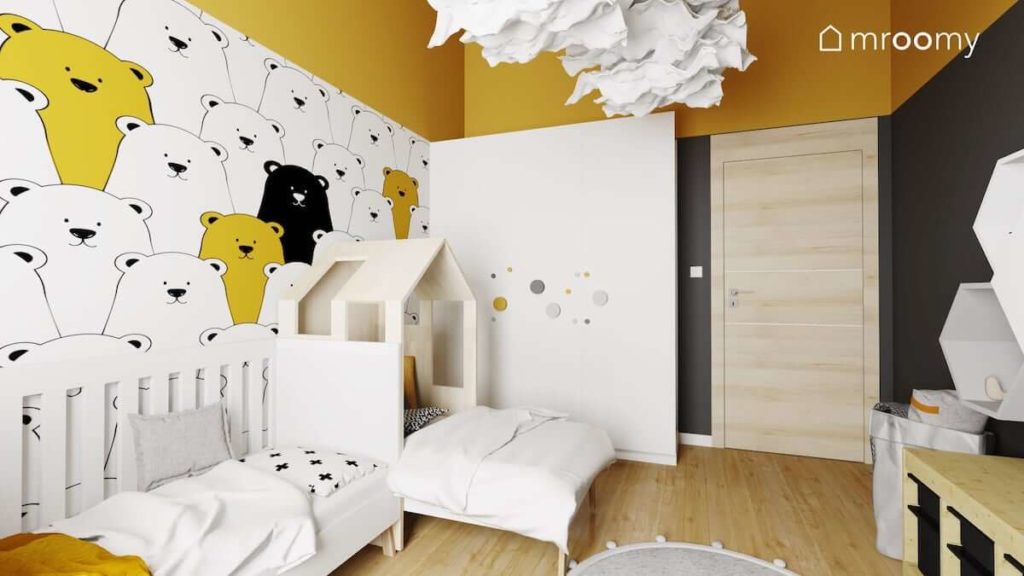 Dwa łóżka na tle tapety w misie szafa z dużymi drewnianymi gałkami i czarno żółte dodatki w pokoju dwójki małych chłopców