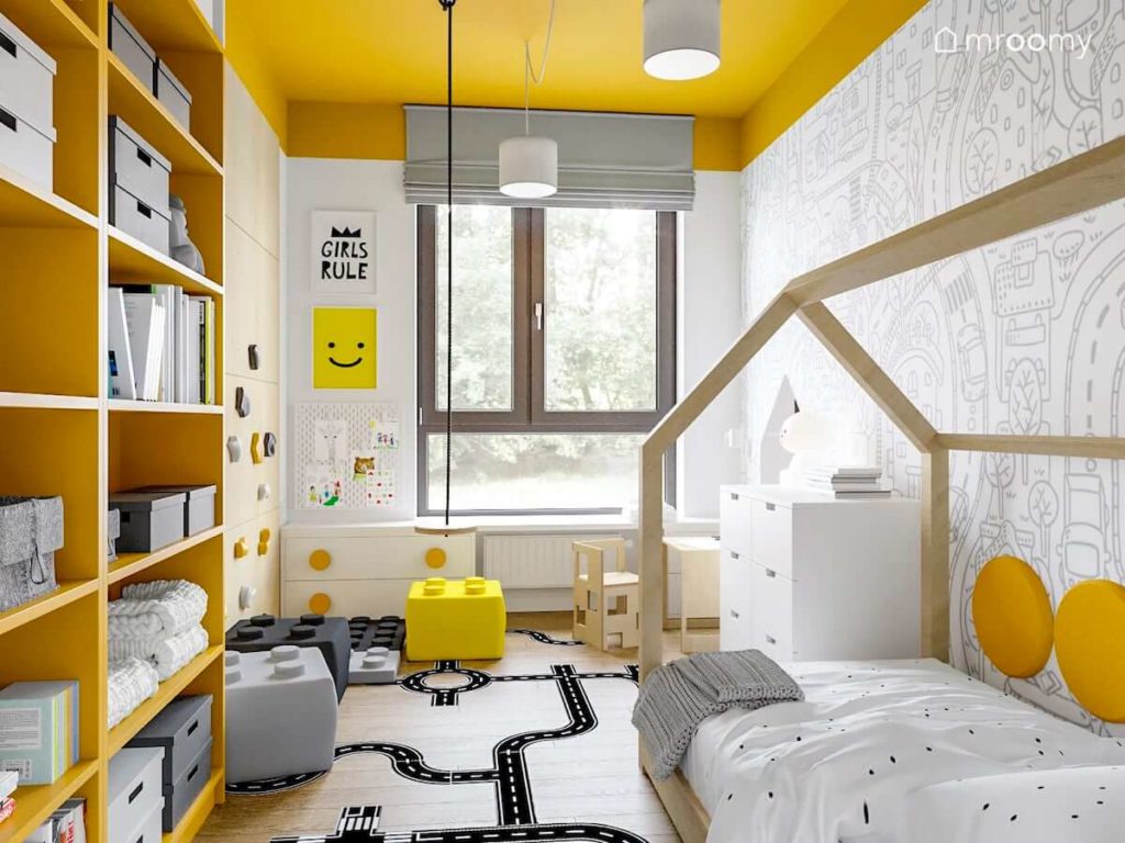 Łóżko domek huśtawka żółte regały i tapeta w miasto i ulice w pokoju dla małego dziecka z żółtym sufitem