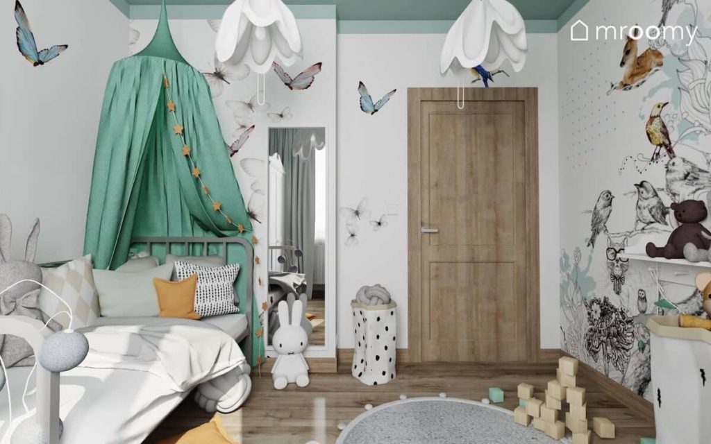 Łóżko z miętowym baldachimem tapeta w motyle i lampka królik w małym pokoju dziewczynki