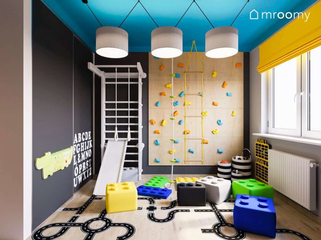 Ścianka wspinaczkowa drabinka gimnastyczna pufy lego i szare ściany w kolorowym pokoju dwójki małych chłopców