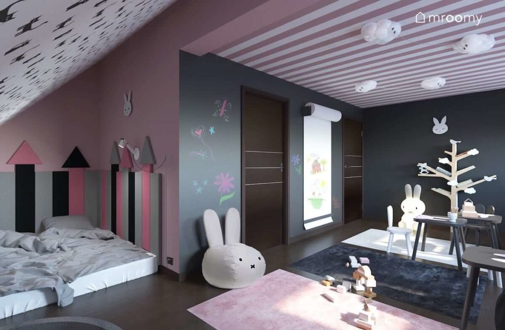 Miejsce do spania pod skosem z miekkimi panelami ściennymi pufą w kształcie królika i dodatkami w kolorach różu i szarości w pokoju dziewczynek
