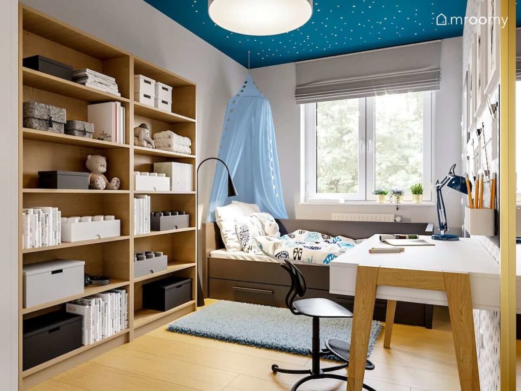 Pokój dla dziewczynki z niebieskim sufitem i fluorescencyjnymi gwiazdkami baldachimem nad łóżkiem i meblami z drewna