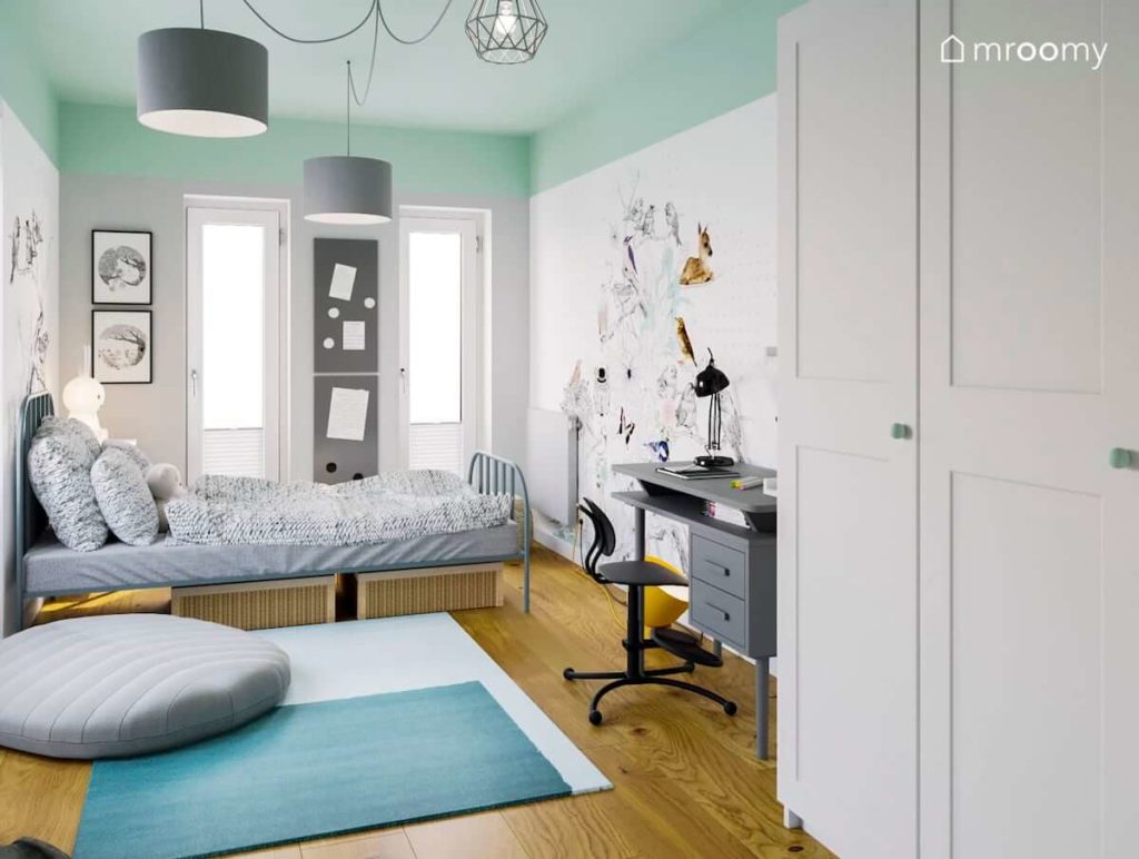 Pokój dla dziewczynki z miętowym sufitem białymi ścianami i dużą naklejką ścienną biurkiem i łóżkiem