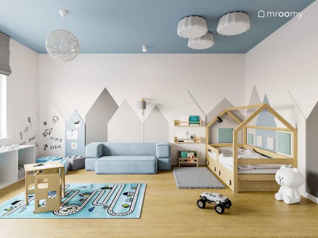 Pokój przedszkolaka z łóżkiem-domkiem sofą dywanem z drogą i okładzinami drewnianymi na ścianie