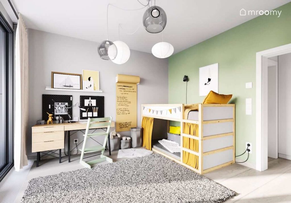 Pokój dziewczynki z zieloną ścianą przy której stoi piętrowe łóżko obok miejsce do pracy z biurkiem a na suficie jest ciekawy zestaw lamp