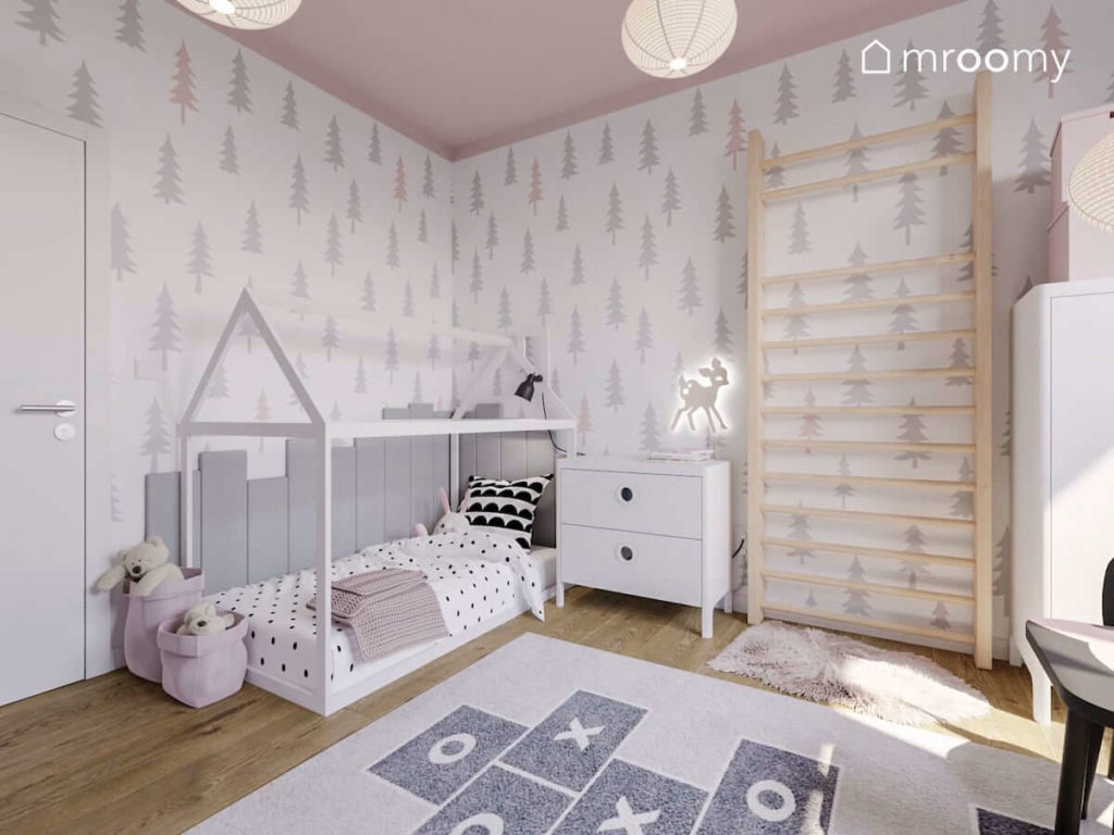 Łóżko domek z panelami ściennymi tapeta w zwierzątka dywan z motywem gry w klasy i różowy sufit w pokoju małej dziewczynki