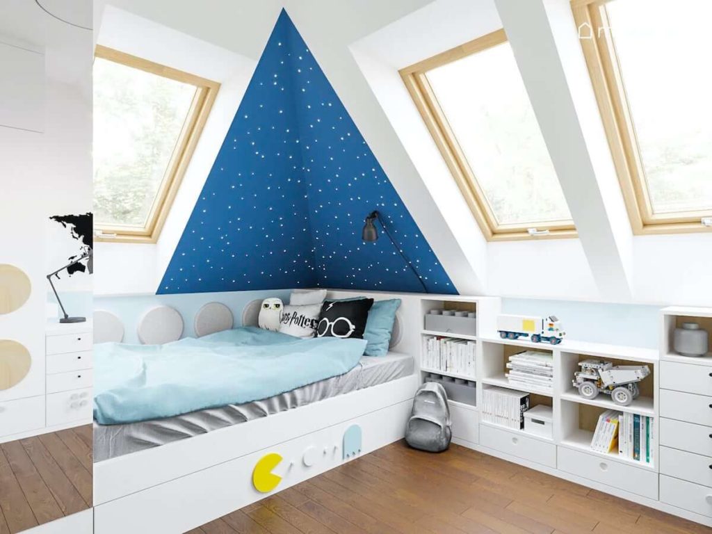 Łóżko przy niebieskiej ścianie z gwiazdkami w pokoju małego chłopca obok regału wykonywanego na zamówienie