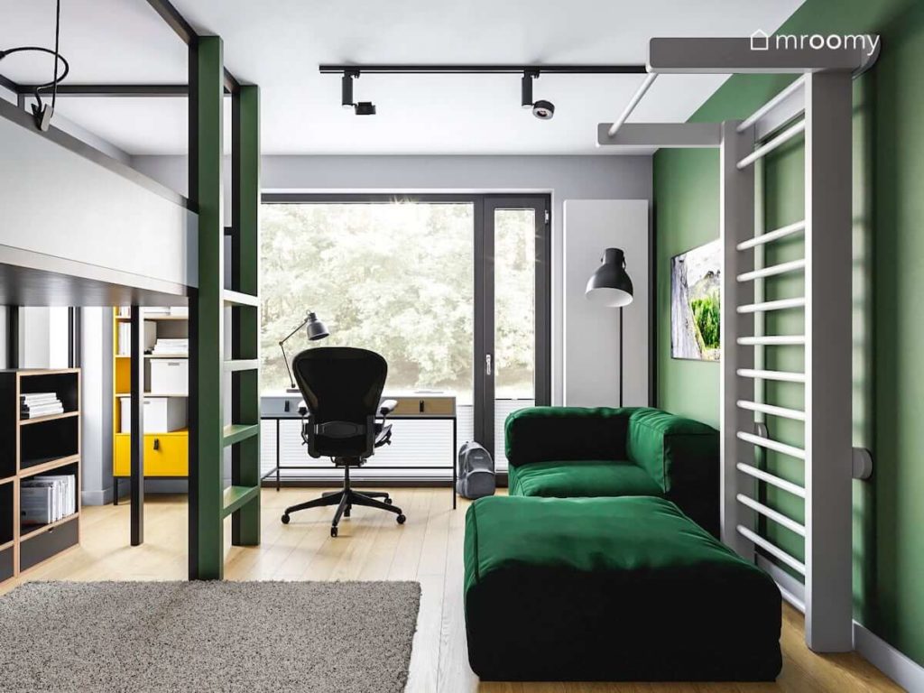 Zielona sofa biurko wygodny fotel przy oknie i drabinka gimnastyczna w pokoju nastolatka