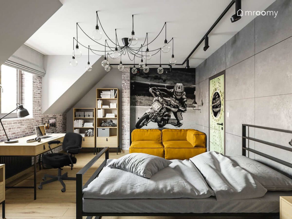 Duży pokój na poddaszu dla nastolatka który interesuje się motocyklami w stylistyce loftowej z kanapą metalowym łóżkiem biurkiem i dużą lampą