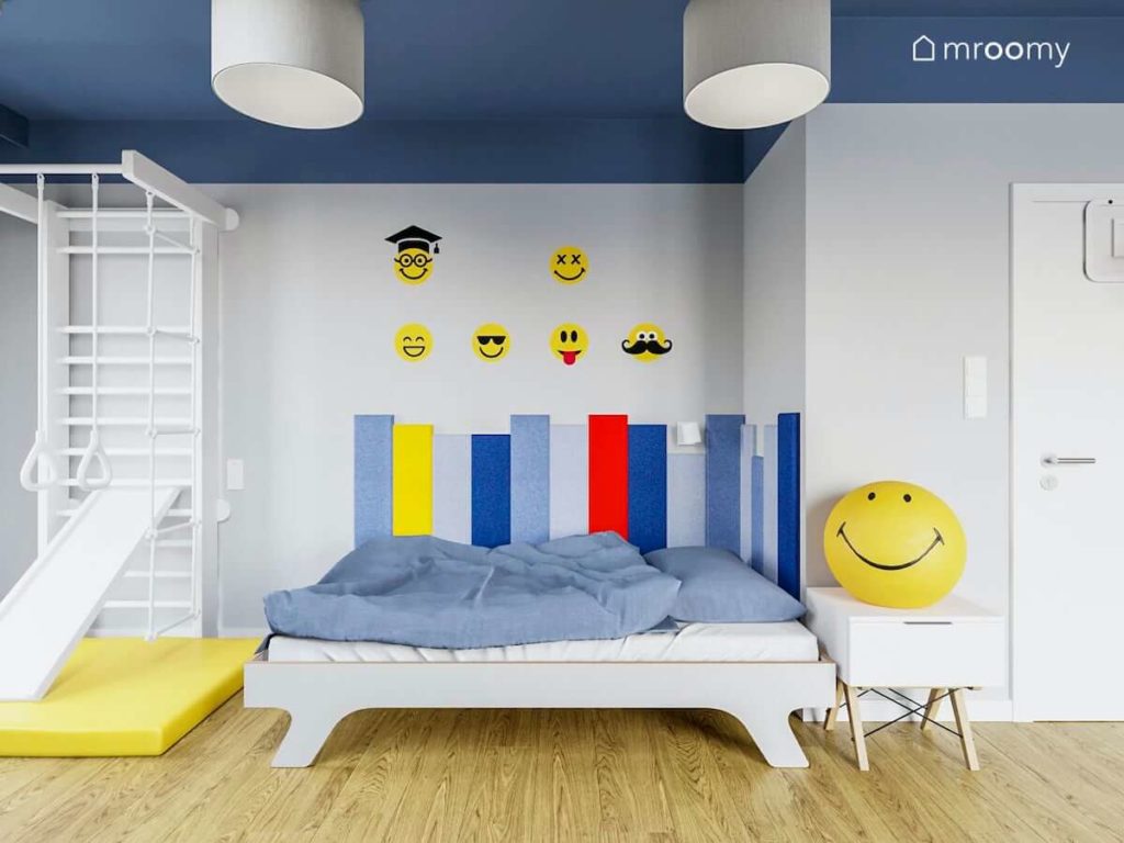Łóżko do spania dla chłopca z szarej sklejki z miękkimi panelami na ścianie i naklejkami w żółte buźki
