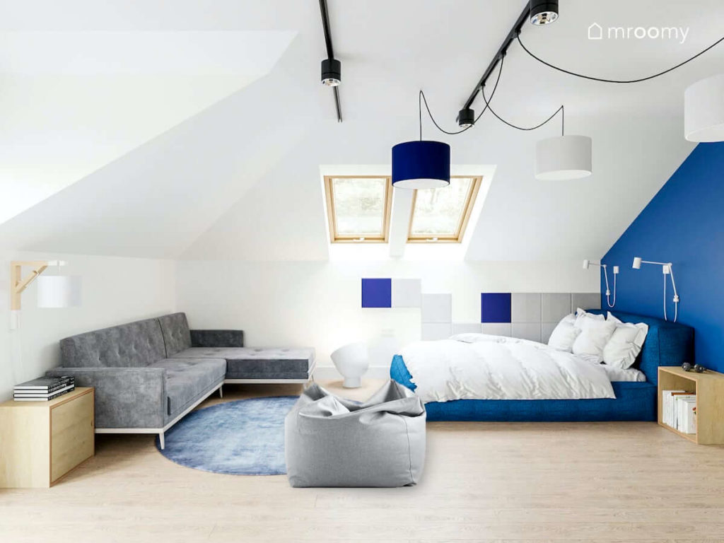 Miękkie duże tapicerowane niebieskie łóżko szafa sofa fotel sako i panele ścienne w pokoju nastolatka na poddaszu