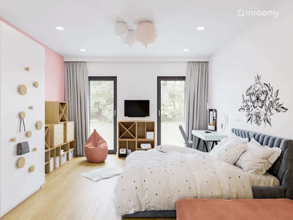 Pokój dla dziewczynki z dużym niebieskim łóżkiem meblami ze sklejki i różowymi ścianami