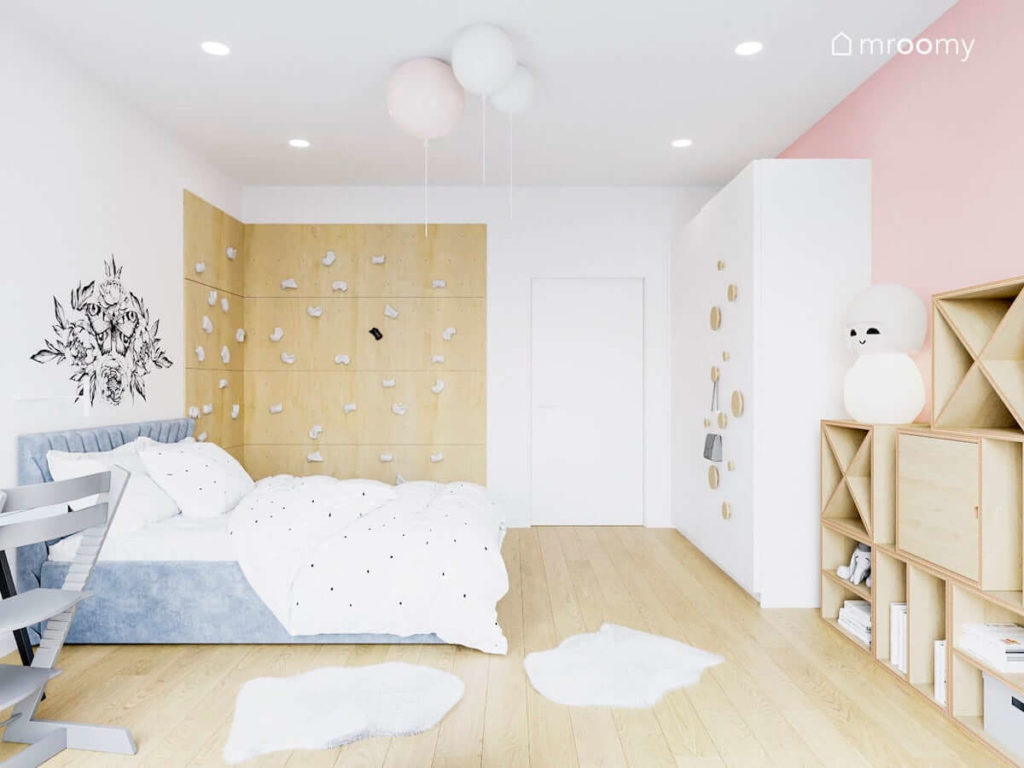 Pokój małej dziewczynki ze ścianką wspinaczkową tapicerowanym łóżkiem i dużą białą szafą z dodanymi uchwytami ze sklejki