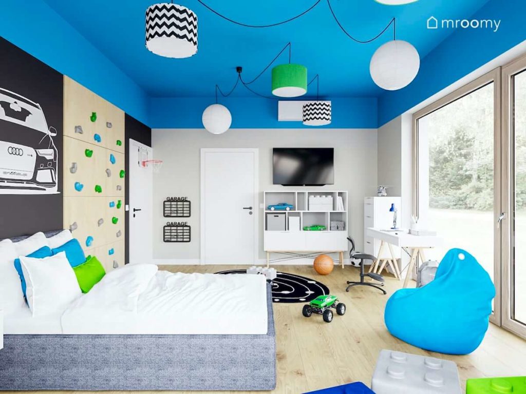 Kolorowe abażury na niebieskim suficie białe meble szare łóżko i niebieski worek sako w pokoju chłopięcym