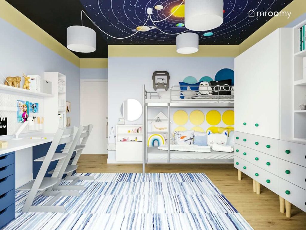Łóżko piętrowe metalowe dywan w paski szafa z kolorowymi gałkami i sufit z planetami w pokoju chłopca i dziewczynki