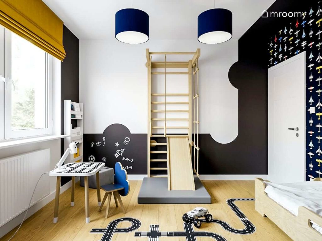 Drabinka stolik z krzesełkiem i czarna farba tablicowa w pokoju chłopca przedszkolaka z naklejkami na podłodze