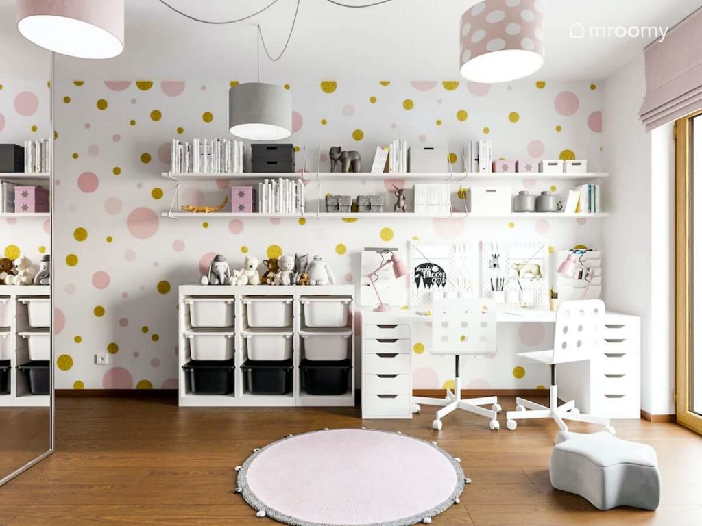 Duże biurko regały na książki w pokoju małych dziewczynek z tapetą w różowe kropki