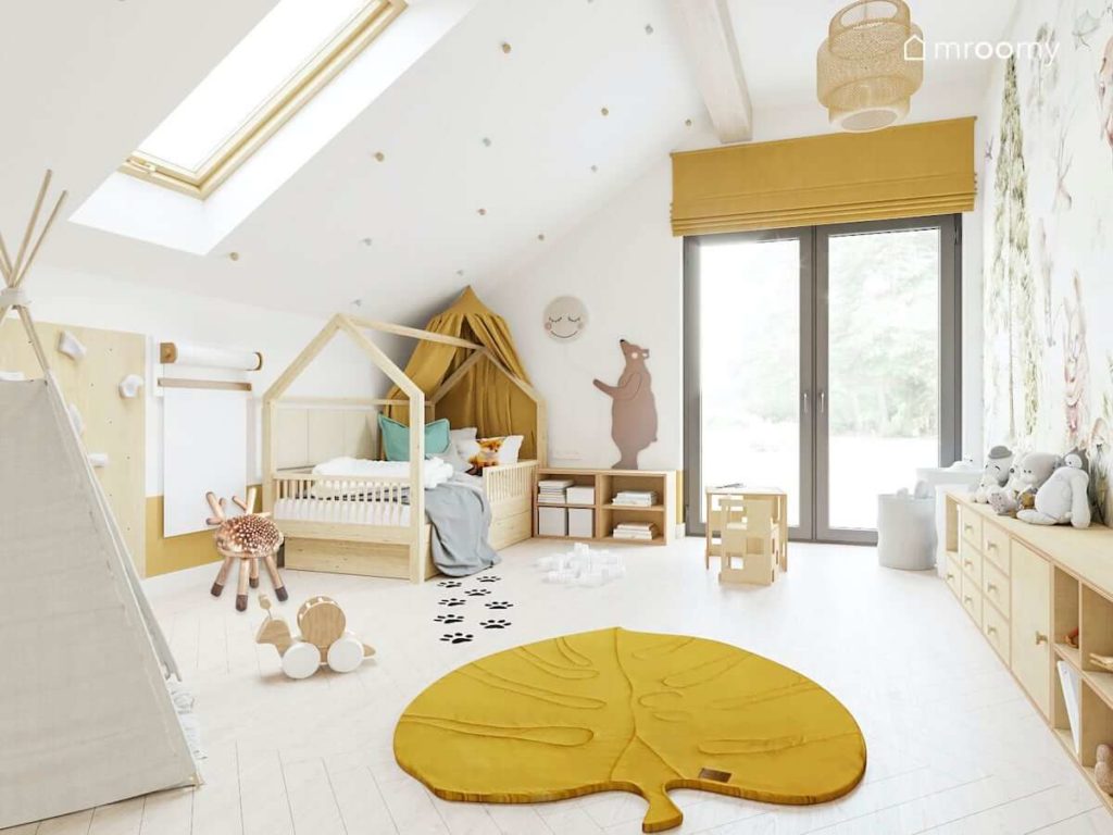 Łóżko domek z musztardowym baldachimem w pokoju małego chłopca w leśnym klimacie i dywanem w kształcie liścia na jasnej drewnianej podłodze
