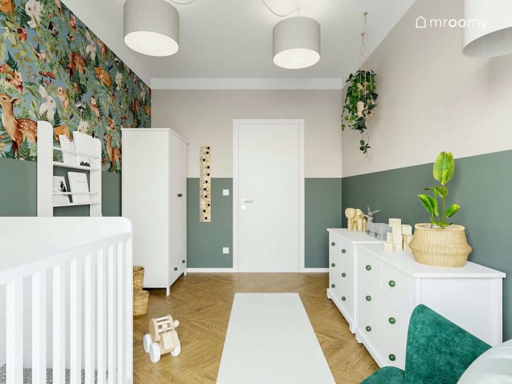 Pokój małego chłopca niemowlaka z butelkową zielenią na ścianach tapetą w zwierzątka i białymi meblami z zielonymi gałkami