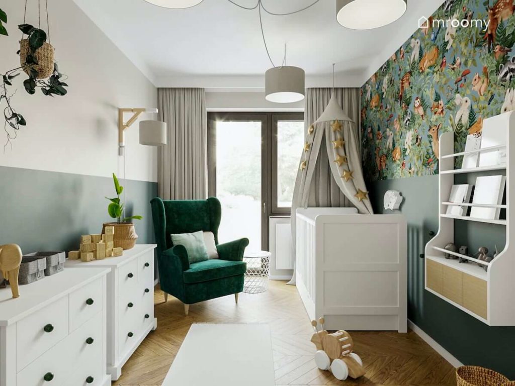 zielony fotel uszak białe łóżko dla niemowlaka i szary baldachim z gidlandą w niewielkiem pokoju dla dziecka
