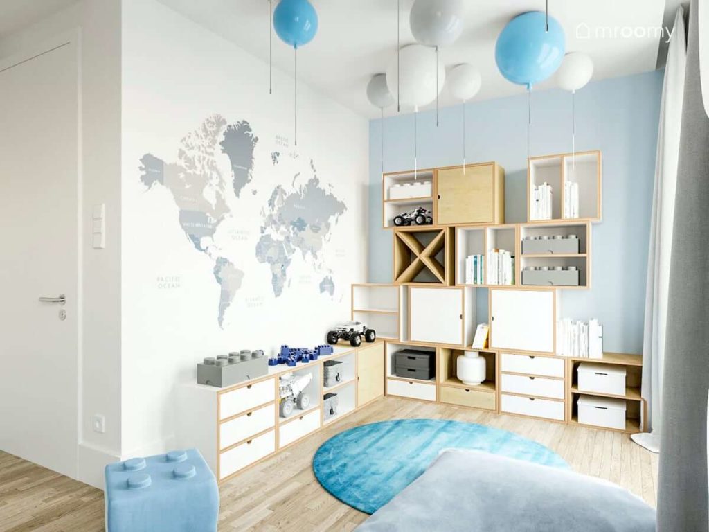 Tapeta z mapą świata modułowe meble ze sklejki naturalnej i białej lampy balony niebieski i szary dywan w pokoju przedszkolaka ucznia