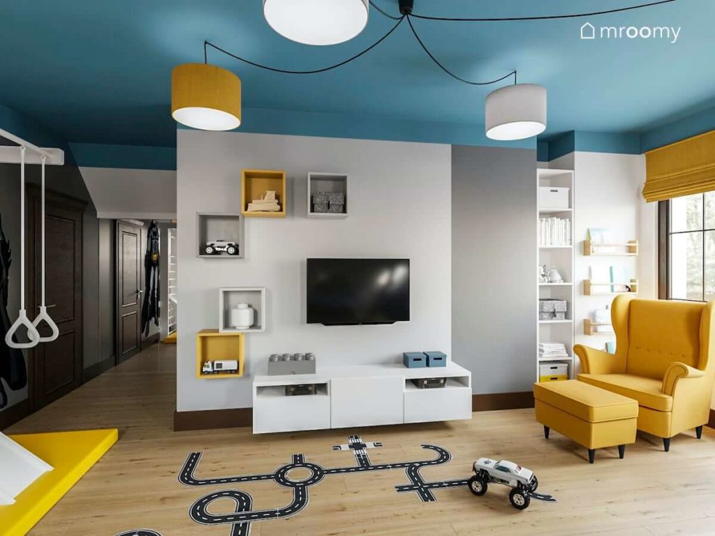 Pokój chłopca ucznia w którym są naklejki podłogowe strefa gier i telewizji niebieski sufit i kolorowe abażury