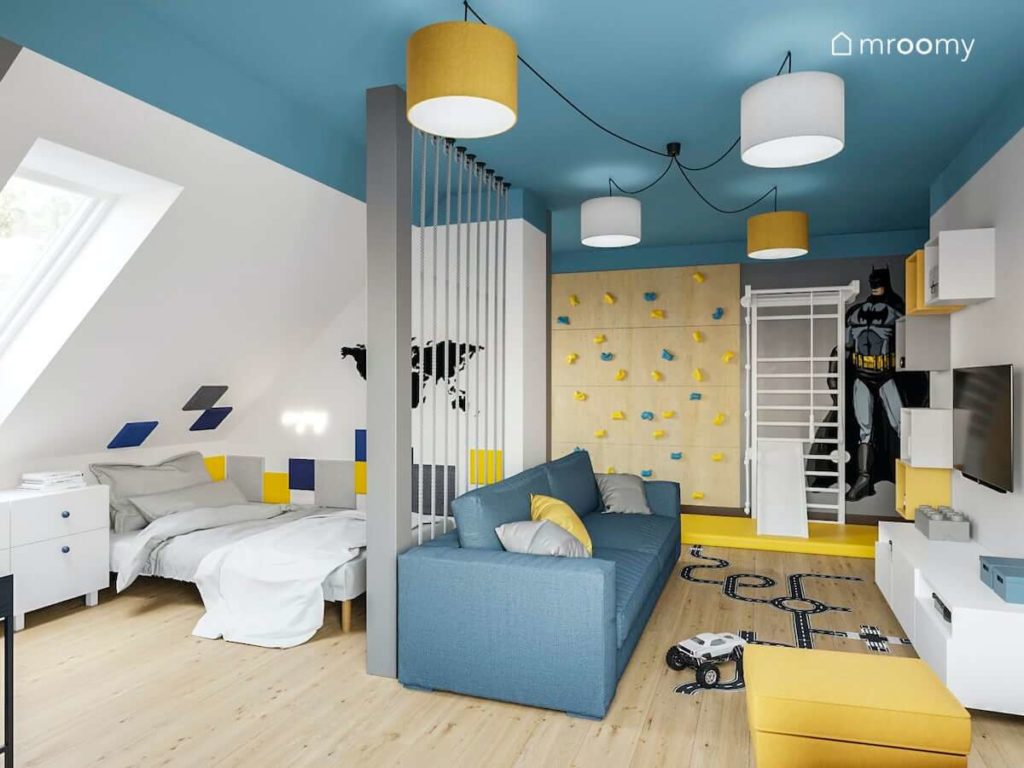 Strefa spania w pokoju chłopca oddzielona od strefy zabawy z sofą ścianką wspinaczkową drabinką gimnastyczną i niebieskim sufitem