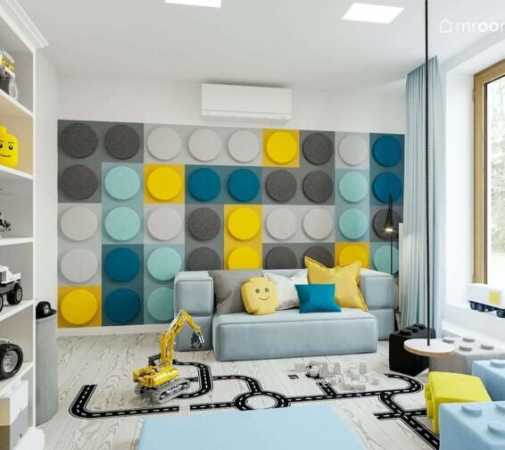 Ściana z miękkich paneli w kształcie klocków lego niebieska sofa naklejki podłogowe i huśtawka w pokoju bawialni dwóch chłopców