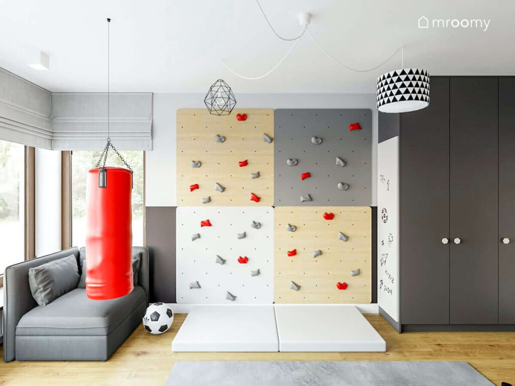 Pokój dla chłopca sportowca ze ścianką wspinaczkową i workiem treningowym szarym modułem kanapy i dużą szafą