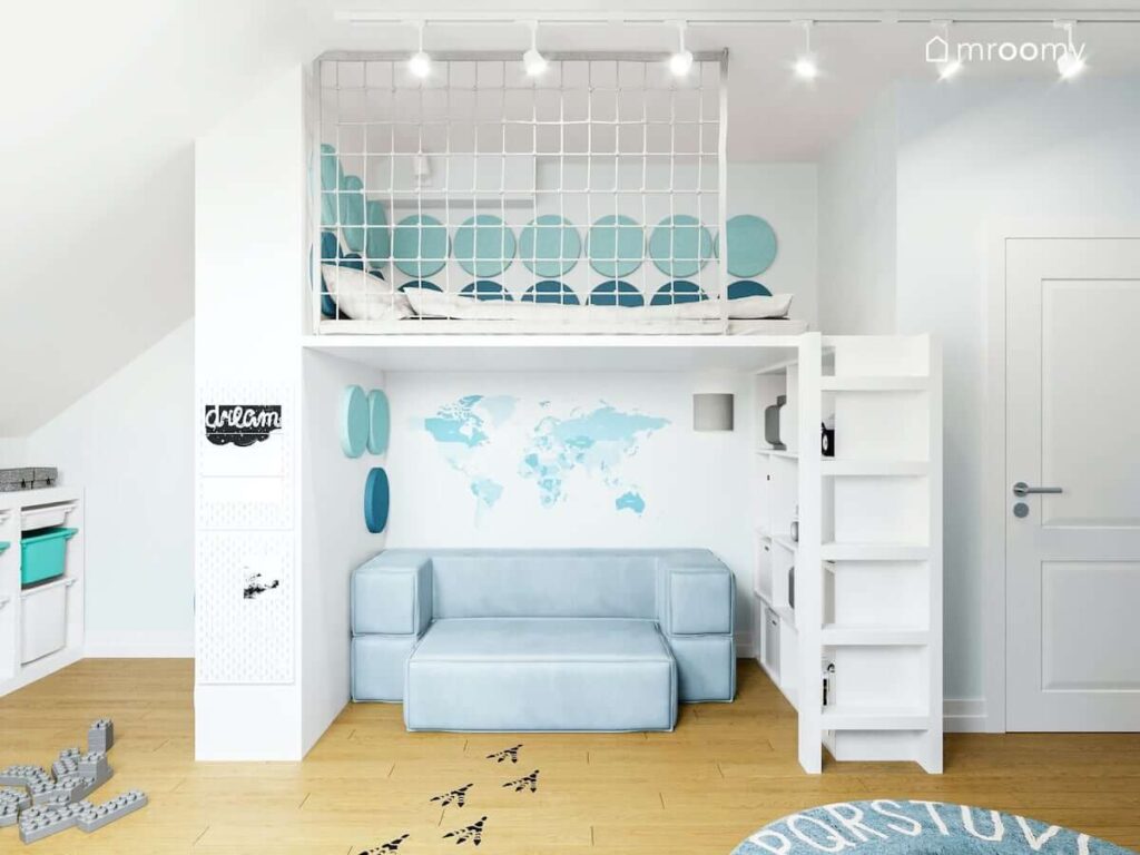 Łóżko na antresoli w pokoju chłopca ściany ozdobione miękkimi panelami ściennymi pod spodem jasnoniebieska sofa i białe regały i naklejka mapa na podłodze naklejki ślady dinozaura