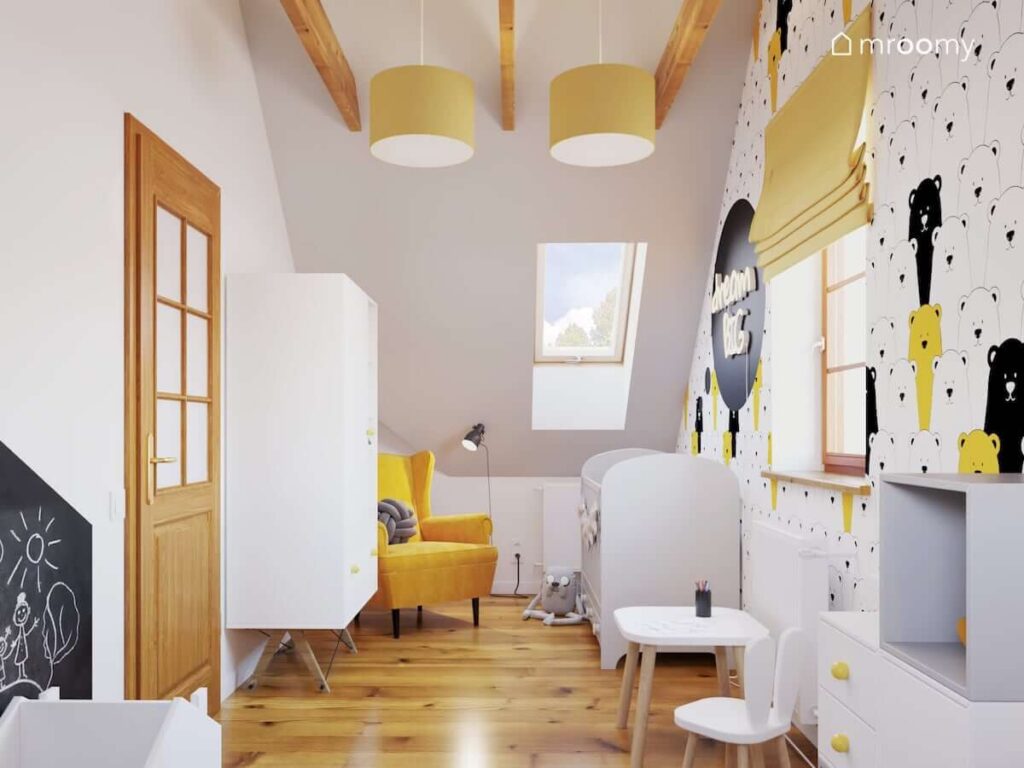 Poddaszowy pokoik dla małego chłopca utrzymany w kolorach białym i żółtym na ścianie tapeta w misie biała szafa na drewnianych nóżkach żółty fotel i żółte abażury w lampach sufitowych