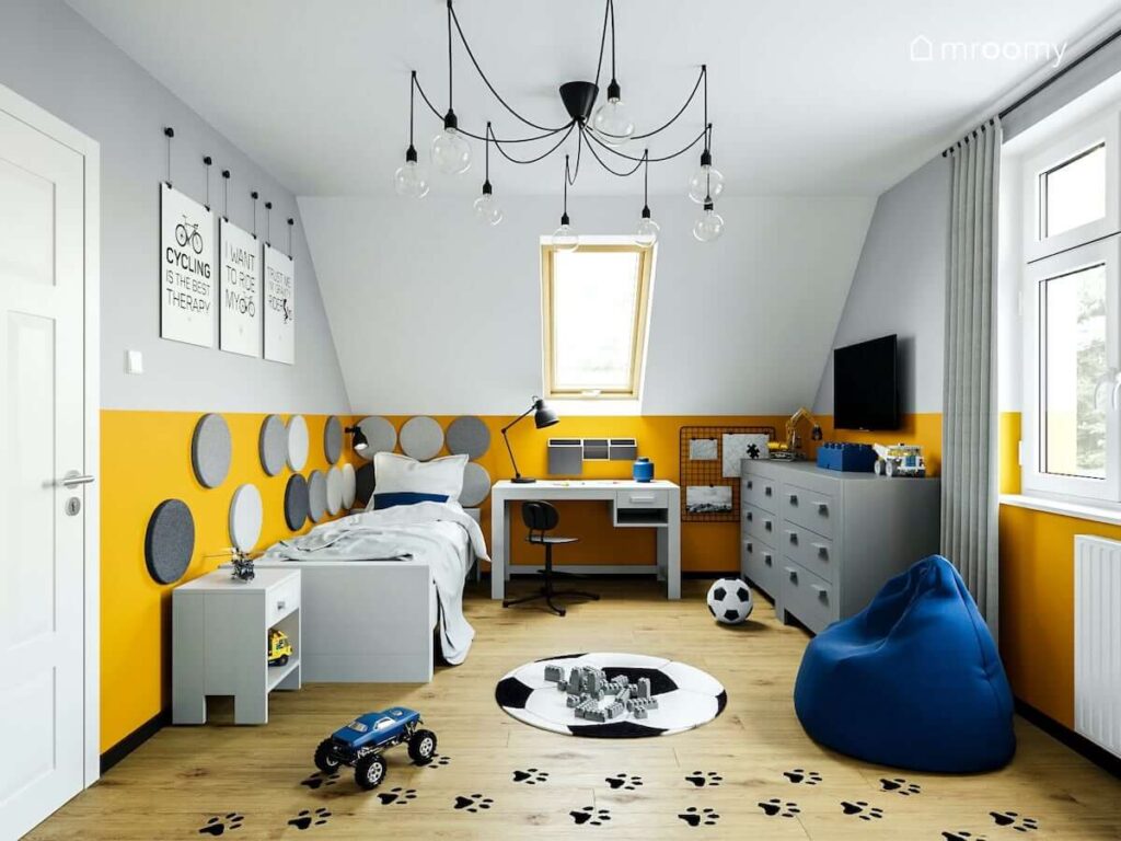Białe biurko łóżko i szara komoda oraz ozdobne plakaty z napisami na ścianie i naklejki w kształcie psich łapek w pokoju dla chłopca