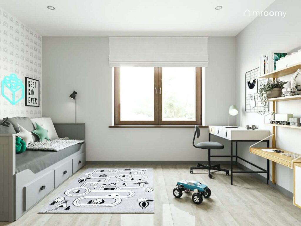 Jasny pokój dla chłopca z rozkładanym łóżkiem z szufladami biurkiem oraz dywanem we wzór w drogę