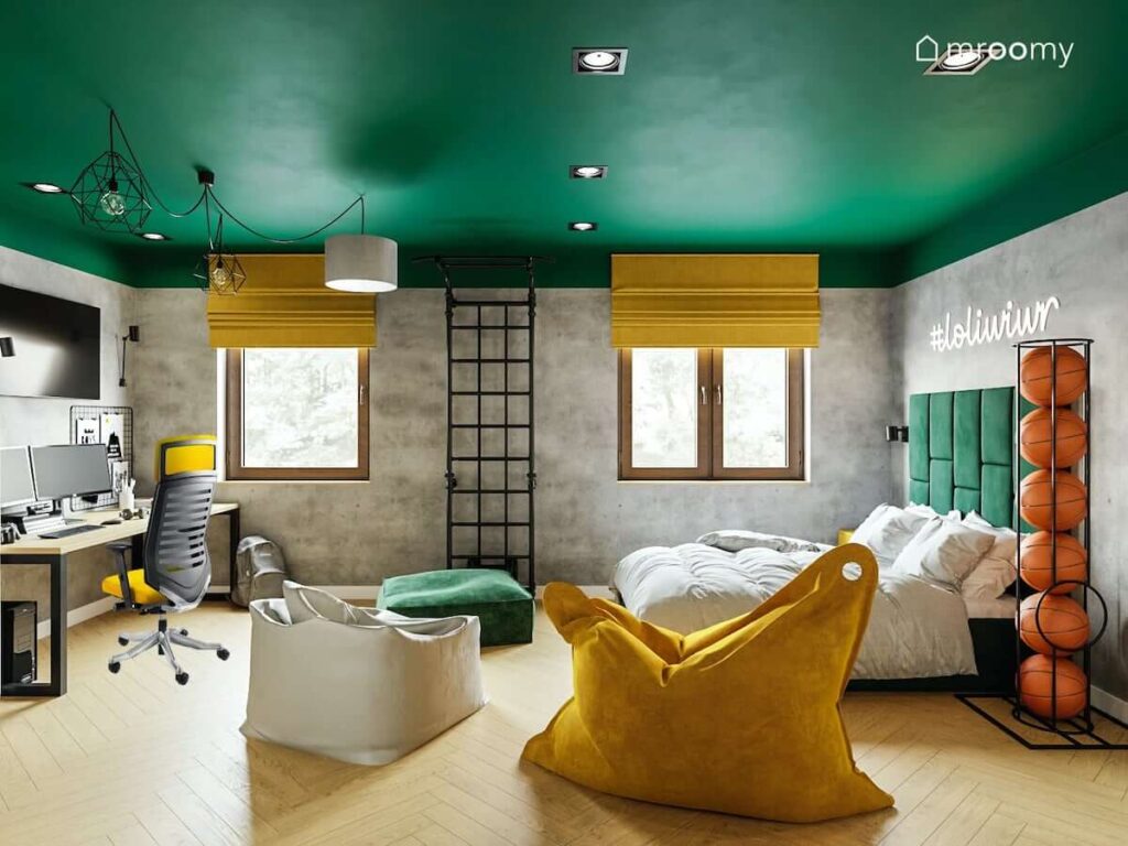 Domowa siłownia kolorowe pufy oraz duże łóżko i biurko a na ścianie ledon z napisem w zielono szaro żółtym pokoju dla nastolatka