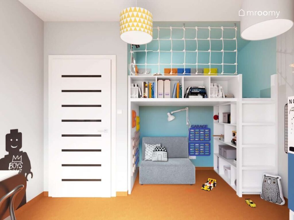 Antresola z półkami oraz łóżkiem na górze i małą sofą na dole a ściany wyłożone kolorowymi panelami ściennymi w kształcie klocków w pokoju dla chłopca