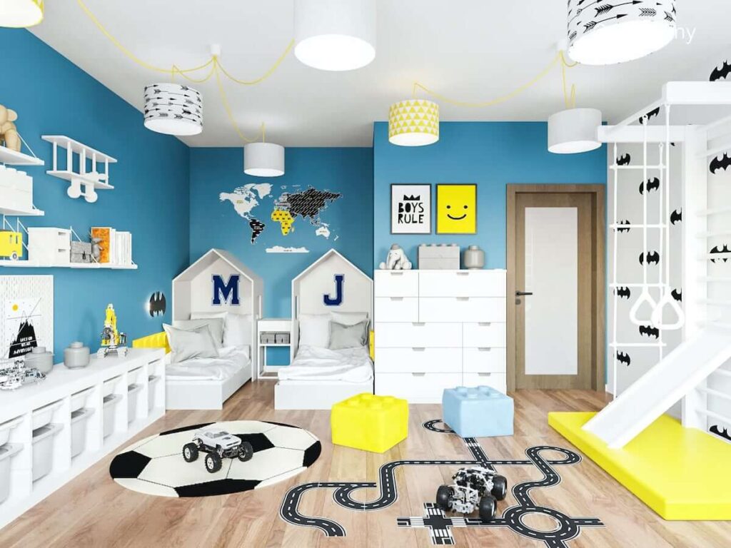 Łóżka w kształcie domków ozdobne plakaty i naklejka na ścianie oraz drabinka gimnastyczna ze zjeżdżalnią w kolorowym pokoju dla dwóch chłopców