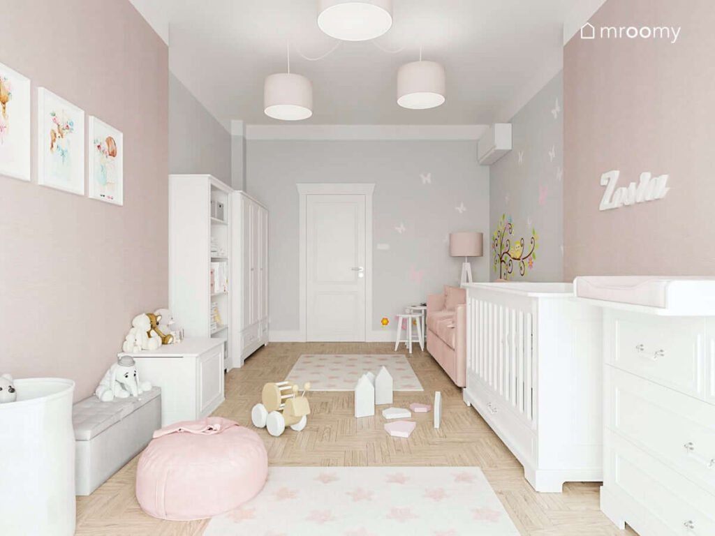 Umeblowany na biało pokój malutkiej dziewczynki ze strefą zabawy uzupełnioną miękkimi dywanami oraz dużą sofą i białym dziecięcym łóżeczkiem