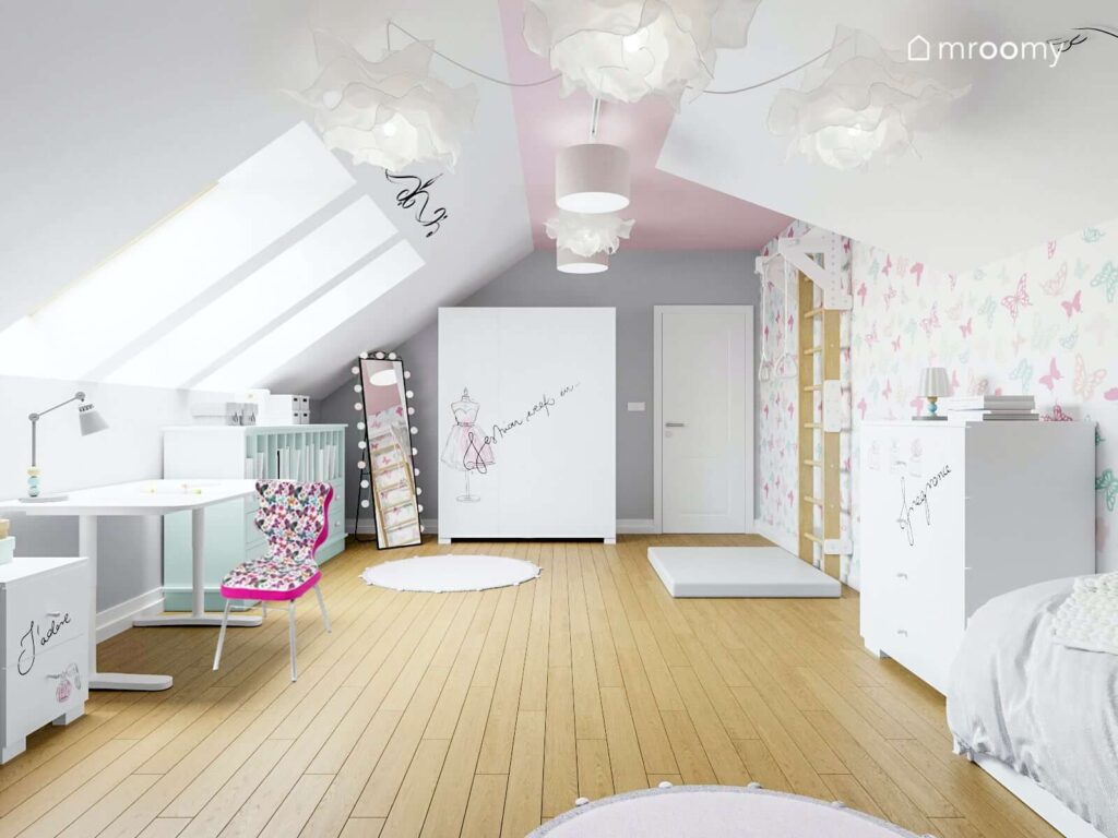 Przestronny poddaszowy pokój dla dziewczynki z drabinką gimnastyczną materacem i dużą białą szafą a także fantazyjnymi lampami sufitowymi