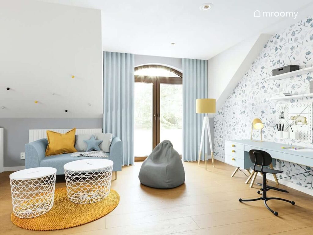 Niebiesko biały pokój z żółtymi dodatkami dla dziewczynki z wygodną sofą oraz pufą a także długim biurkiem