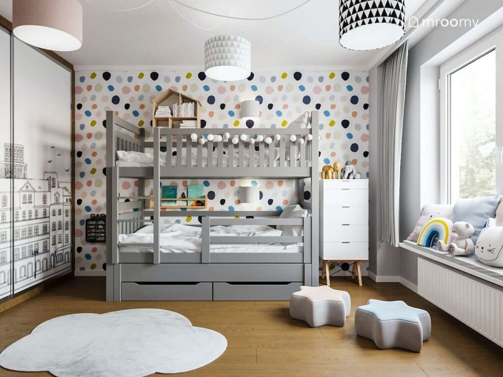 Grafitowe łóżko piętrowe w pokoju rodzeństwa ozdobione girlandą cotton balls a na ścianie wesoła tapeta w kropki u sufitu lampy z kolorowymi abażurami